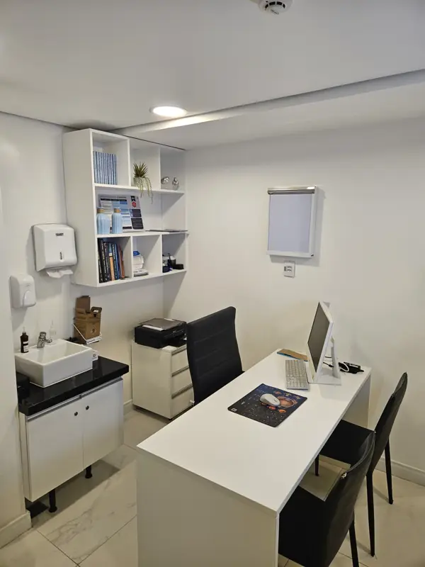 Consultório com mesa, pia e estante