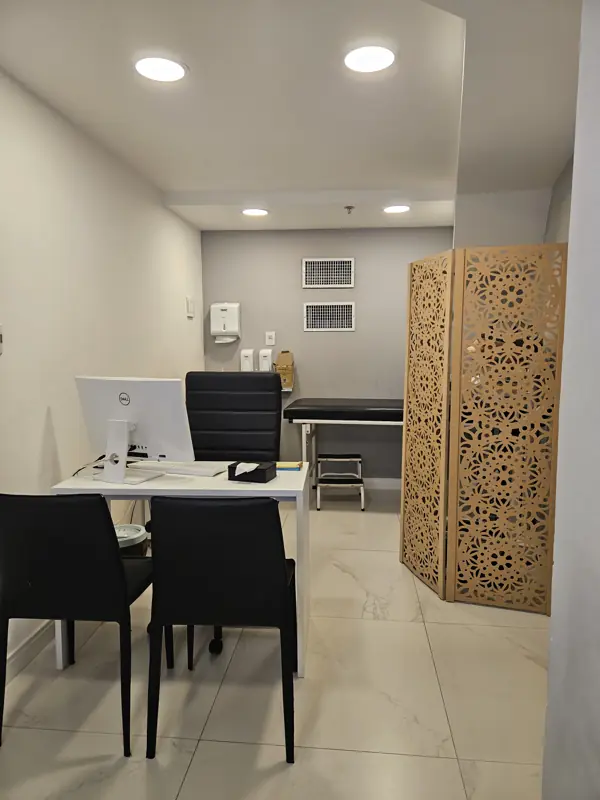 Consultório da SER com mesa, computador e biombo de madeira